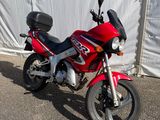 une moto rouge garée devant une tente blanche