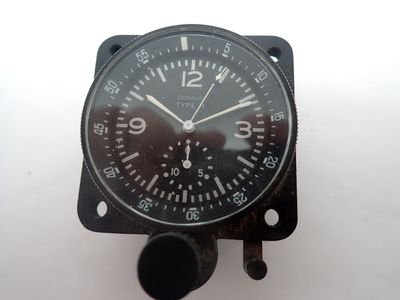 une horloge noire posée sur une surface blanche, avec un fond blanc