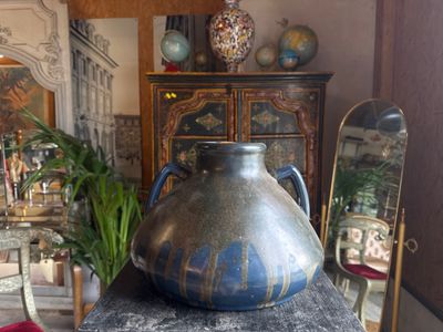 a large vase sitting on top of a table in front of a mirror