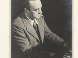 portrait of a man in a suit and tie sitting at a piano