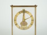 une image représentant une horloge dorée dans une vitrine, sur fond blanc