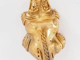 gold figurine of a woman sitting on a tree branch