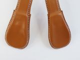 pair of brown leather slippers with white stitching on them