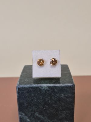une paire de boucles d'oreilles en or posée sur un bloc de marbre