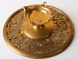 a gold plate with a candle holder on top of it