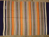 an orange, blue and white striped rug on the floor