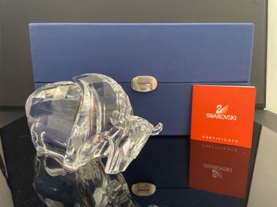 une figurine d'éléphant en verre posée sur une table, à côté d'une boîte bleue