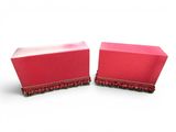 pair of red boxes with fringe trims on a white background