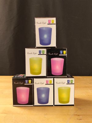 trois boîtes de bougies empilées les unes sur les autres sur une table en bois