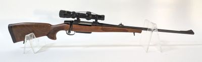 le fusil est posé sur un support transparent équipé d'une lunette de visée