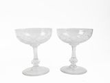 two wine glasses sitting next to each other on a white surface