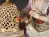 a figurine of a woman with a parrot in her hand