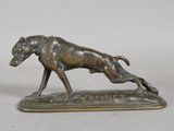 a bronze statue of a dog running on top of a wooden base