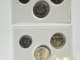 four different british coins are in a clear box on a white surface