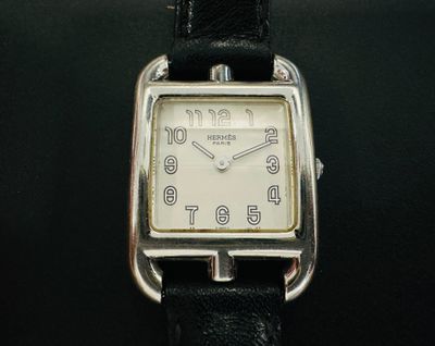 une montre argentée avec un bracelet noir posée sur une surface noire
