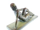 bronze statue of a woman laying on her stomach on a marble base