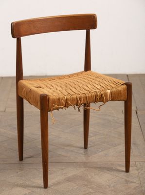 un gros plan d'une chaise à l'assise tressée posée sur un parquet