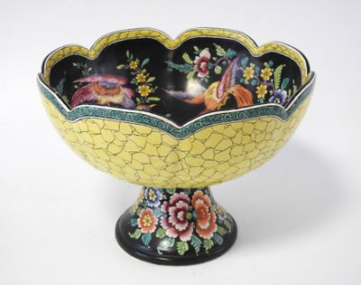 a yellow and black bowl with birds and flowers on it