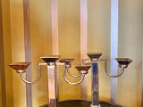 une table sur laquelle sont posées trois bougies, dans une pièce aux murs rayés
