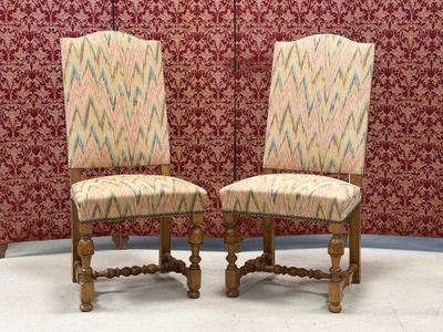 pair of upholstered chairs in front of a red wallpapered wall