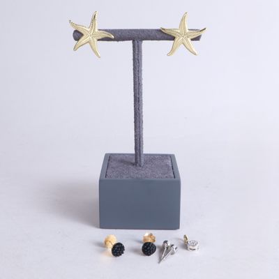 une paire de boucles d'oreilles en forme d'étoile dorée posée sur un support à côté d'une paire de vis