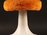 an image of a white pedestal with an orange furry hat on top