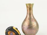 a vase next to a measuring tape on a white surface