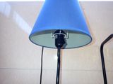 a blue lamp that is on a table next to a wall