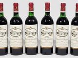 six bottles of wine are lined up in a row on a white surface