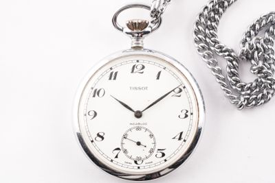 une montre de poche en argent, suspendue à une chaîne, posée sur une surface blanche