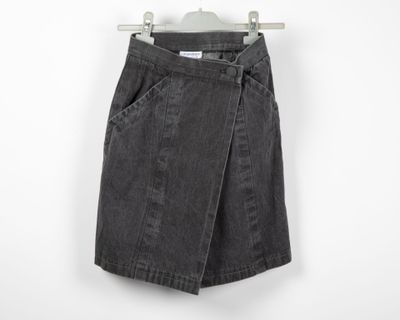 a black denim skirt hanging on a hanger against a white wall
