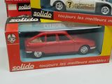 a red toy car in a box on a white surface