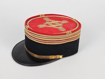 un chapeau rouge et noir orné d'un emblème doré