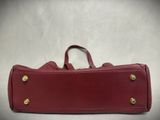 red leather case with brass hardware on top of it on a white background