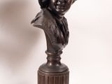 bronze bust of a woman with a hat on top of a pedestal