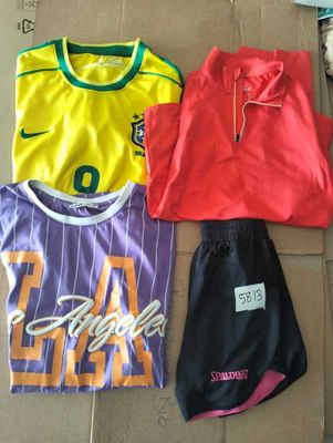 three soccer jerseys and a pair of shorts on a cardboard box