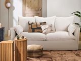 un salon avec un canapé blanc et un pouf marron