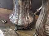 a silver pitcher sitting on top of a table next to other silverware