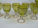 six green glass goblets are lined up on a table