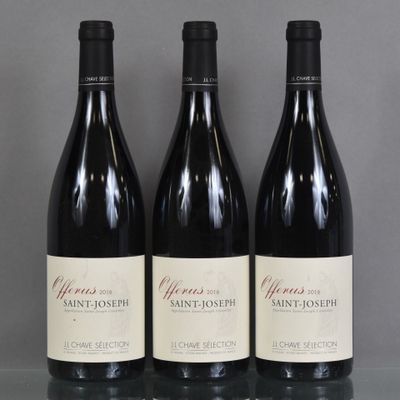 Trois bouteilles de vin sont alignées sur une table en verre