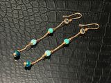 une paire de boucles d'oreilles en perles d'or et de turquoise sur fond noir
