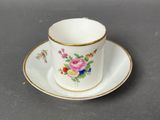 a white cup and saucer with a floral design on it