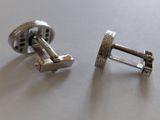 pair of silver cufflinks on a table with a white background