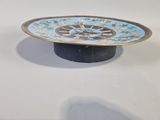 a blue and gold plate sitting on a black stand
