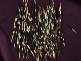 a pile of black and gold toothpicks on a purple cloth