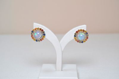 a pair of oplite and sapphire earrings on a white stand