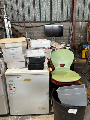 un tas d'appareils électroménagers et une chaise dans un entrepôt