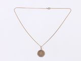 a close up of a gold necklace with a coin on it
