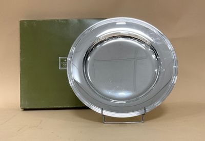 une assiette en argent posée sur une table, à côté d'une boîte verte