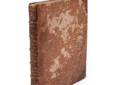 an old book with a brown cover sitting on top of a white surface